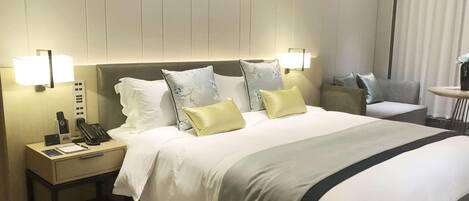 A hotel room with a large bed, bedside lamps, a nightstand with a phone and a lamp, and a small table with a vase.