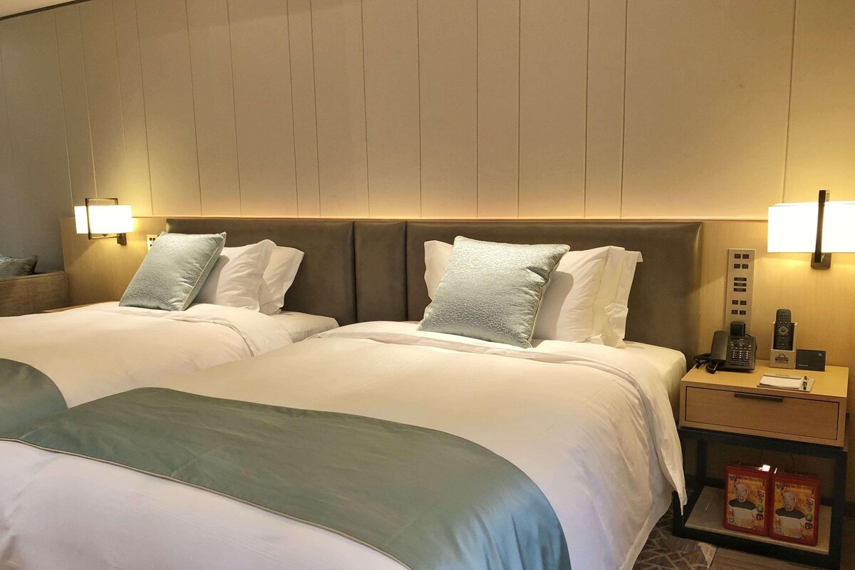 Une chambre d’hôtel avec deux lits, des lampes de chevet, une table de chevet avec un téléphone et une boîte de mouchoirs.