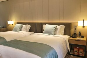 Una habitación de hotel con dos camas, lámparas de noche, una mesita de noche con un teléfono y una caja de pañuelos.