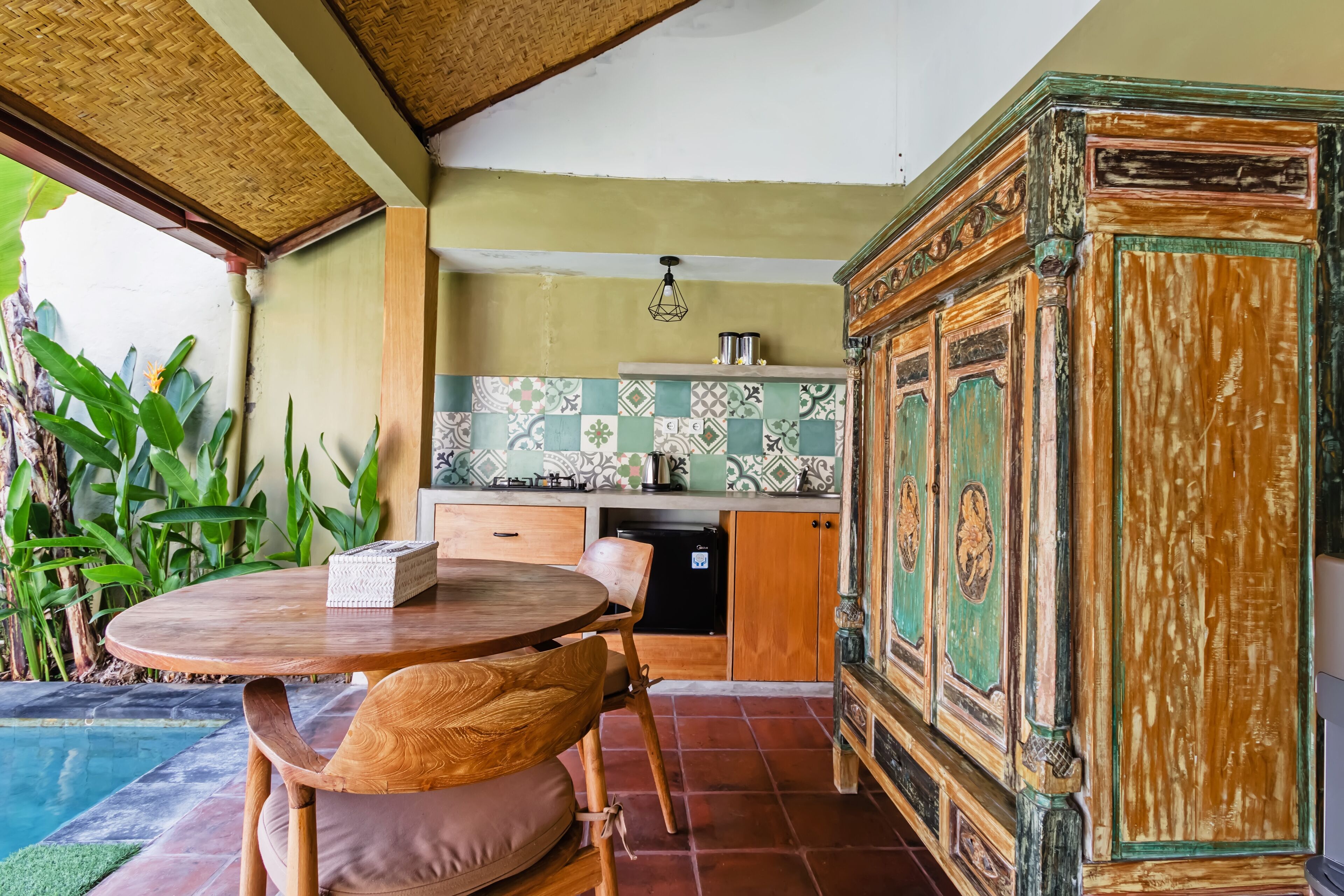 A kitchen with a tiled backsplash, wooden cabinets, and a dining area with a table and chairs.