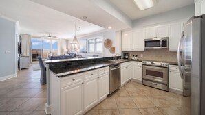 A modern kitchen with white cabinets, stainless steel appliances, and a large island. - Azure 118 ~ 4BR Beachfront Ground Floor Corner Condo ~ Sleeps 14 ~ Must See! (Fort Walton Beach)