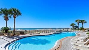 A swimming pool with lounge chairs and palm trees, surrounded by a paved deck. - Azure 118 ~ 4BR Beachfront Ground Floor Corner Condo ~ Sleeps 14 ~ Must See! (Fort Walton Beach)