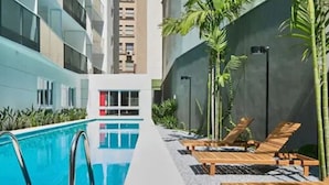 Un área de piscina interior moderna con una piscina cristalina, sillones de descanso y plantas en macetas.