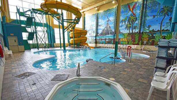 Ein Hallenbad mit Rutsche, Wandgemälde und Whirlpool.