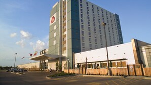 Ein mehrstöckiges Hotel mit einem gut sichtbaren 'Crown'-Logo, einer überdachten Eingangszone und einem Parkplatz.
