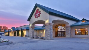 A Canada Inns hotel with a prominent red maple leaf logo, stone pillars, and a blue roof. - Canad Inns Destination Centre Portage la Prairie (Portage La Prairie)