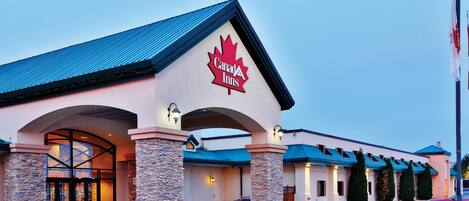 A Canada Inn hotel with a prominent maple leaf logo, stone pillars, and a blue roof.