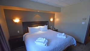 A hotel room with a large bed, two bedside tables, and wall-mounted lamps. - Canad Inns Destination Centre Portage la Prairie (Portage La Prairie)