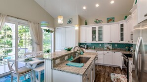 Una cocina moderna con armarios blancos, encimera de granito y refrigerador de acero inoxidable.
