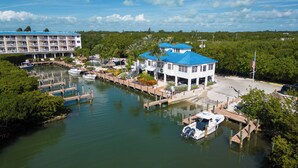 A marina with docked boats, a white building with blue roofs, and a large hotel in the background. - 2306 Ocean Pointe Suites - Quality Decor with Ocean Views (Tavernier)