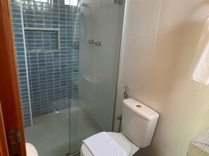 A bathroom with a glass-enclosed shower, a toilet, and a sink. - Excelentes Duplex Maceió (Maceió)