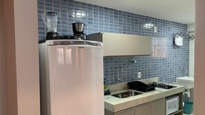 A kitchen with a refrigerator, stove, sink, and blue tiled backsplash. - Excelentes Duplex Maceió (Maceió)