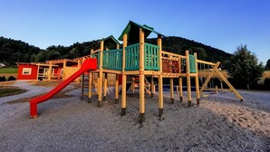 Un parque infantil con un tobogán rojo y una estructura de madera para escalar.