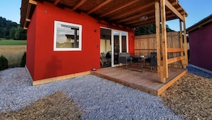 Un edificio rojo con terraza de madera y un porche cubierto.