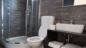 Un baño moderno con ducha de vidrio, inodoro y tocador con lavabo y espejo.