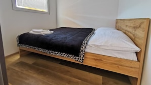 Una cama individual con cabecera de madera, colcha negra con estampado de jirafa y almohadas blancas.