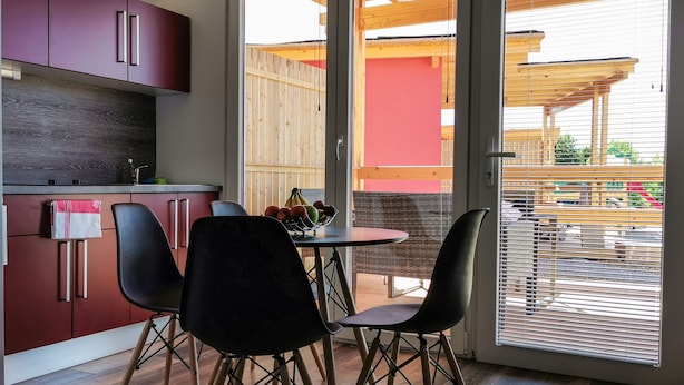 Una cocina moderna con armarios rojos y un comedor con mesa y sillas.