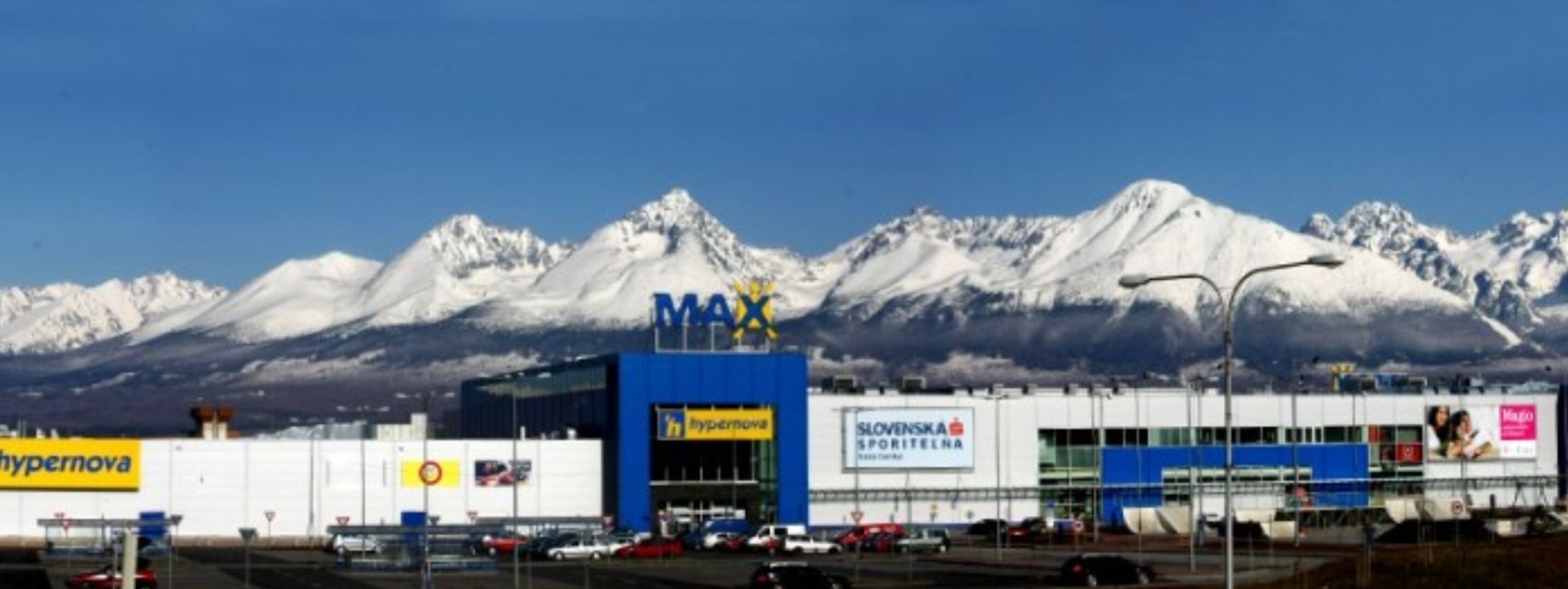 A commercial building with a MAX sign, a hypernova store, and a Slovenská sportelna sign.