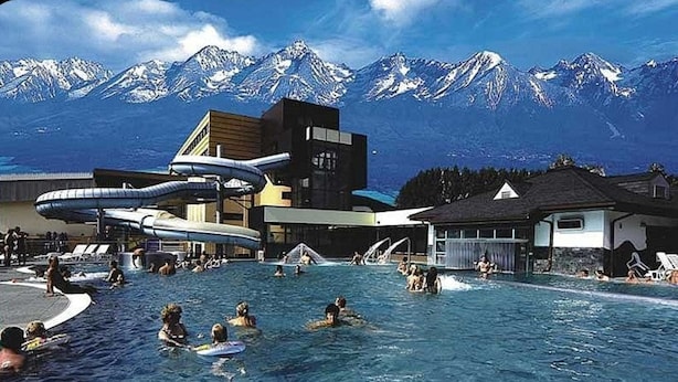 Un área de piscina con toboganes y montañas al fondo.