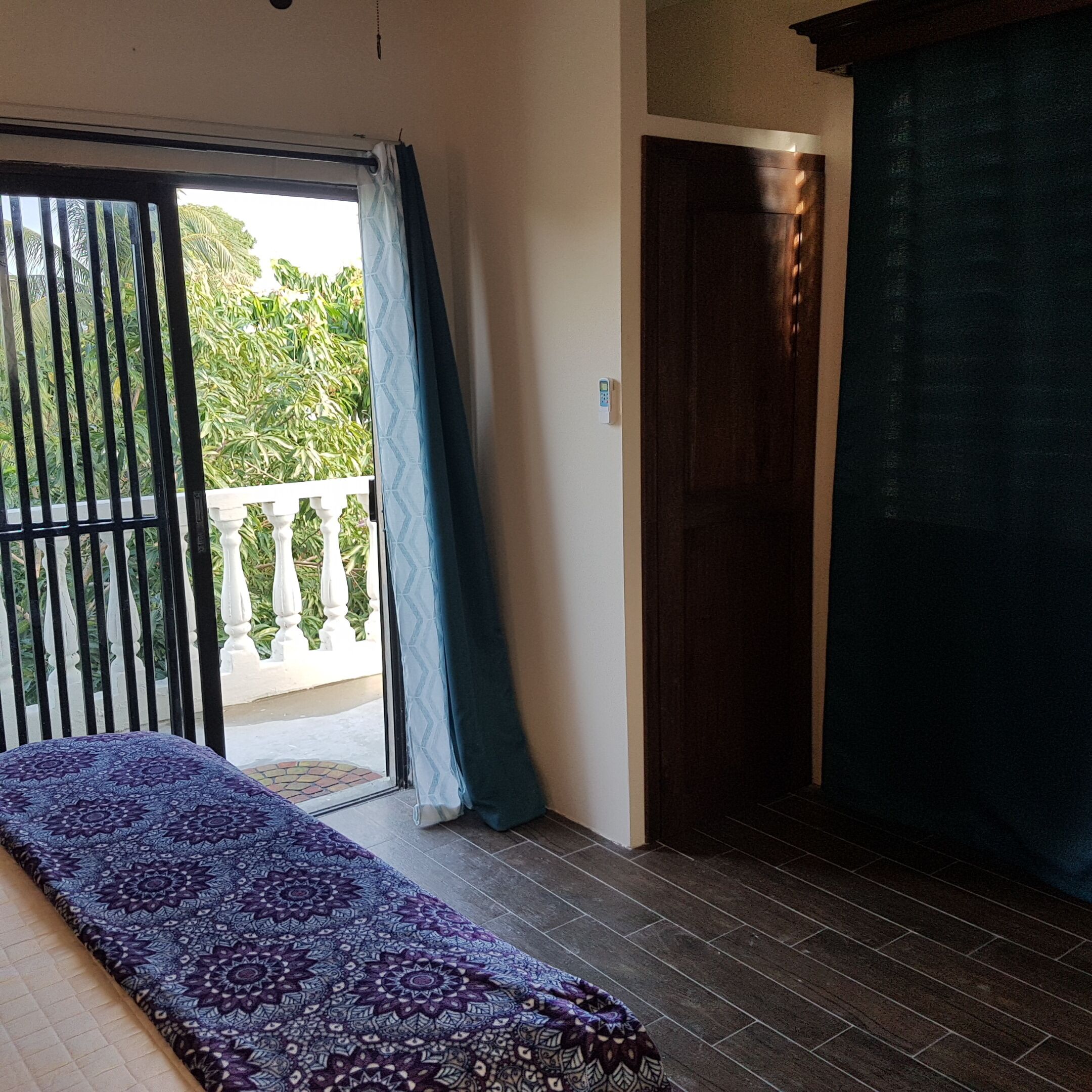 A room with a bed, a sliding door, and a view of greenery outside.