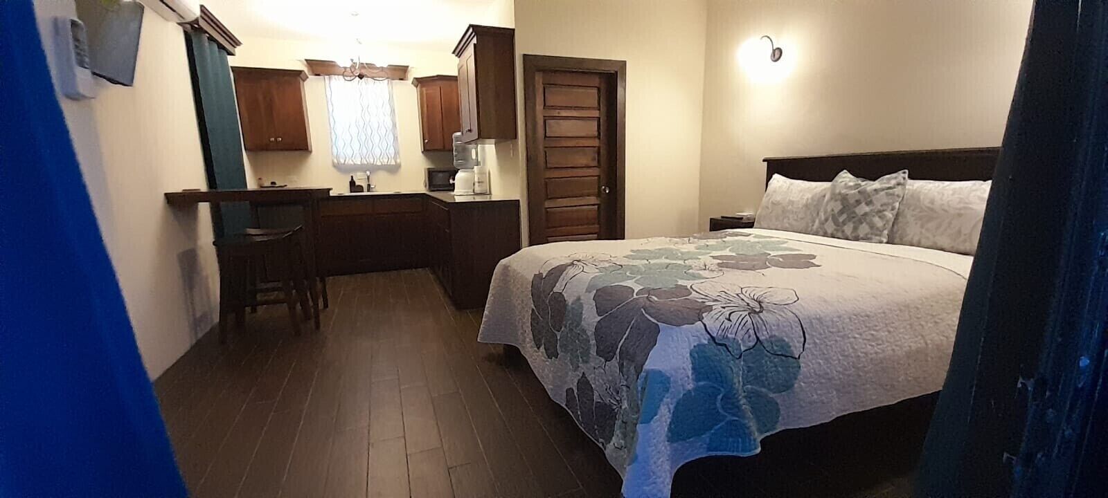 Ein Schlafzimmer mit einem Bett, einem Schreibtisch, einem Stuhl, einem Nachttisch und einem Fenster mit Vorhängen.