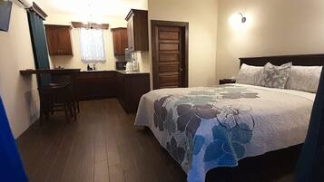 Ein Schlafzimmer mit einem Bett, einem Schreibtisch, einem Stuhl, einem Nachttisch und einem Fenster mit Vorhängen.