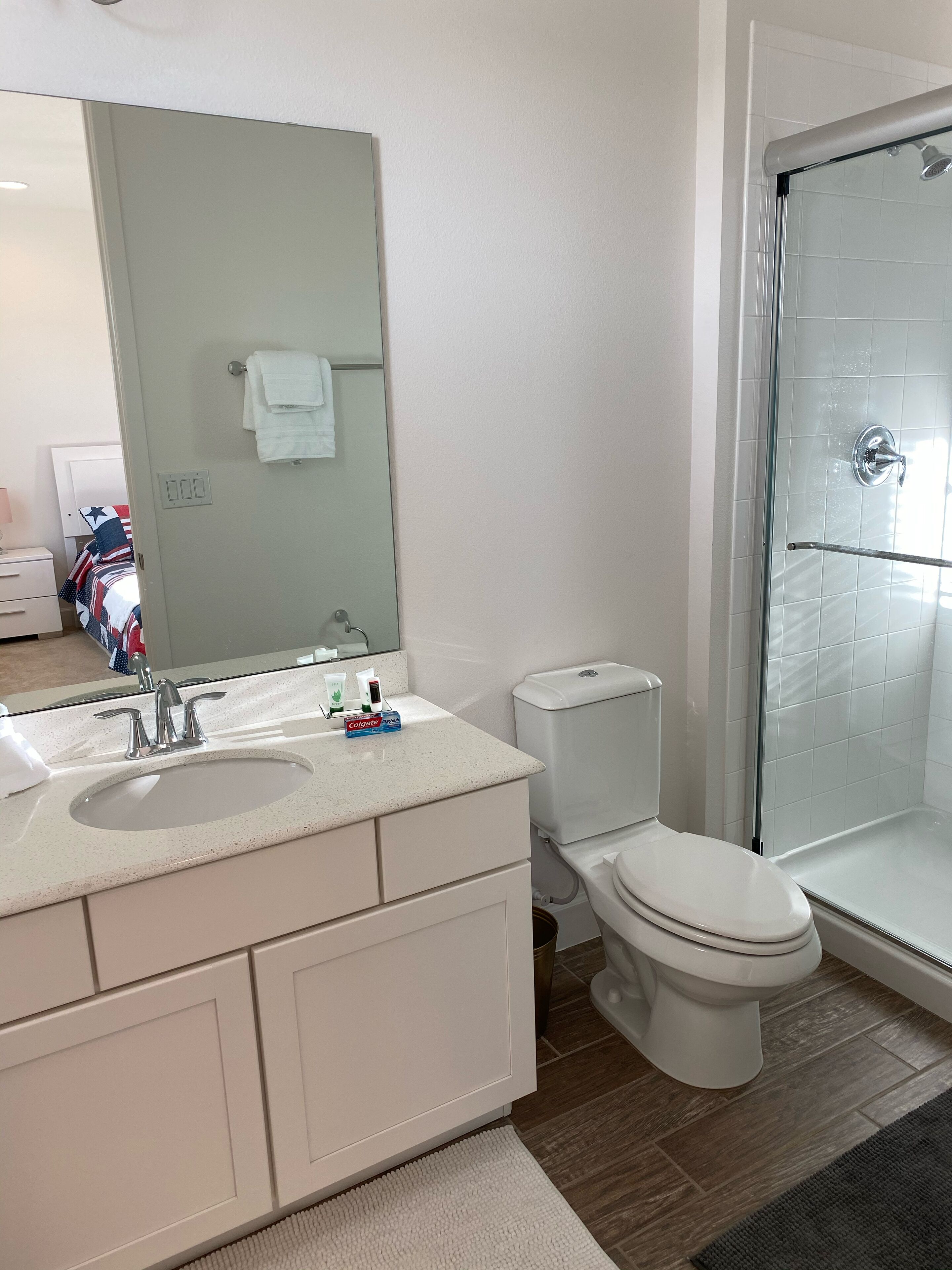 A modern bathroom with a double sink vanity, a toilet, and a glass-enclosed shower.