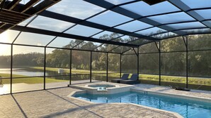 Área da piscina com hidromassagem, espreguiçadeiras e vista para um lago.