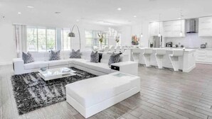 Ampla sala de estar com um sofá seccional branco grande, uma mesa de centro e um tapete preto e branco.