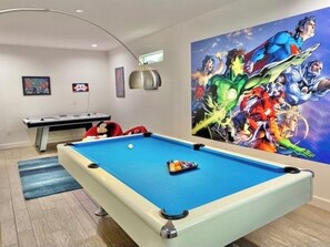 Une table de billard avec une fresque colorée représentant des super-héros en arrière-plan.
