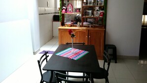 A dining area with a wooden table and chairs, a kitchen in the background, and a bar area with various bottles and decorations. - Shanell House - Hostel (Cusco)