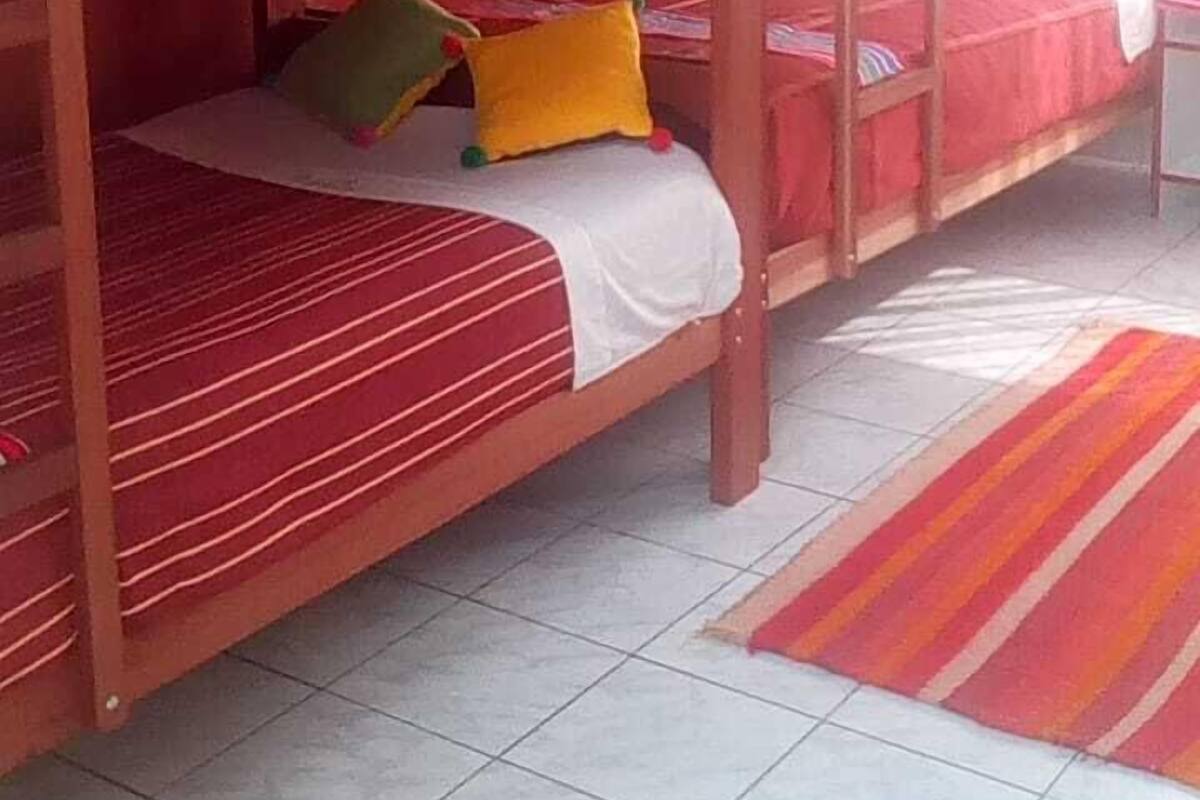 A room with bunk beds, a tiled floor, and a colorful striped rug.