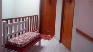 A hallway with a wooden bench, a red patterned rug, and two wooden doors with decorative figures. - Shanell House - Hostel (Cusco)