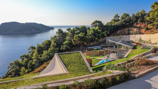 Una propiedad frente al mar con piscina, jardín y vistas al océano.