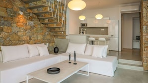Un salon moderne avec un mur en pierre, un canapé blanc et une table basse au design minimaliste.