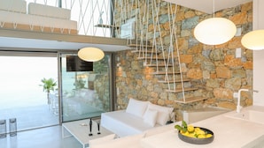 Une pièce moderne avec un mur en pierre, un canapé blanc, une table à manger et un saladier rempli de citrons.