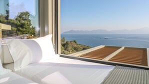 Une chambre moderne dotée d’une grande fenêtre donnant sur une vue panoramique de la côte.