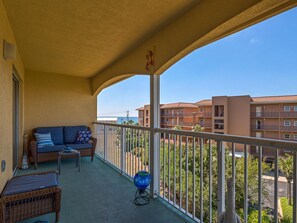 A balcony with a wicker sofa, a small table, and a globe.