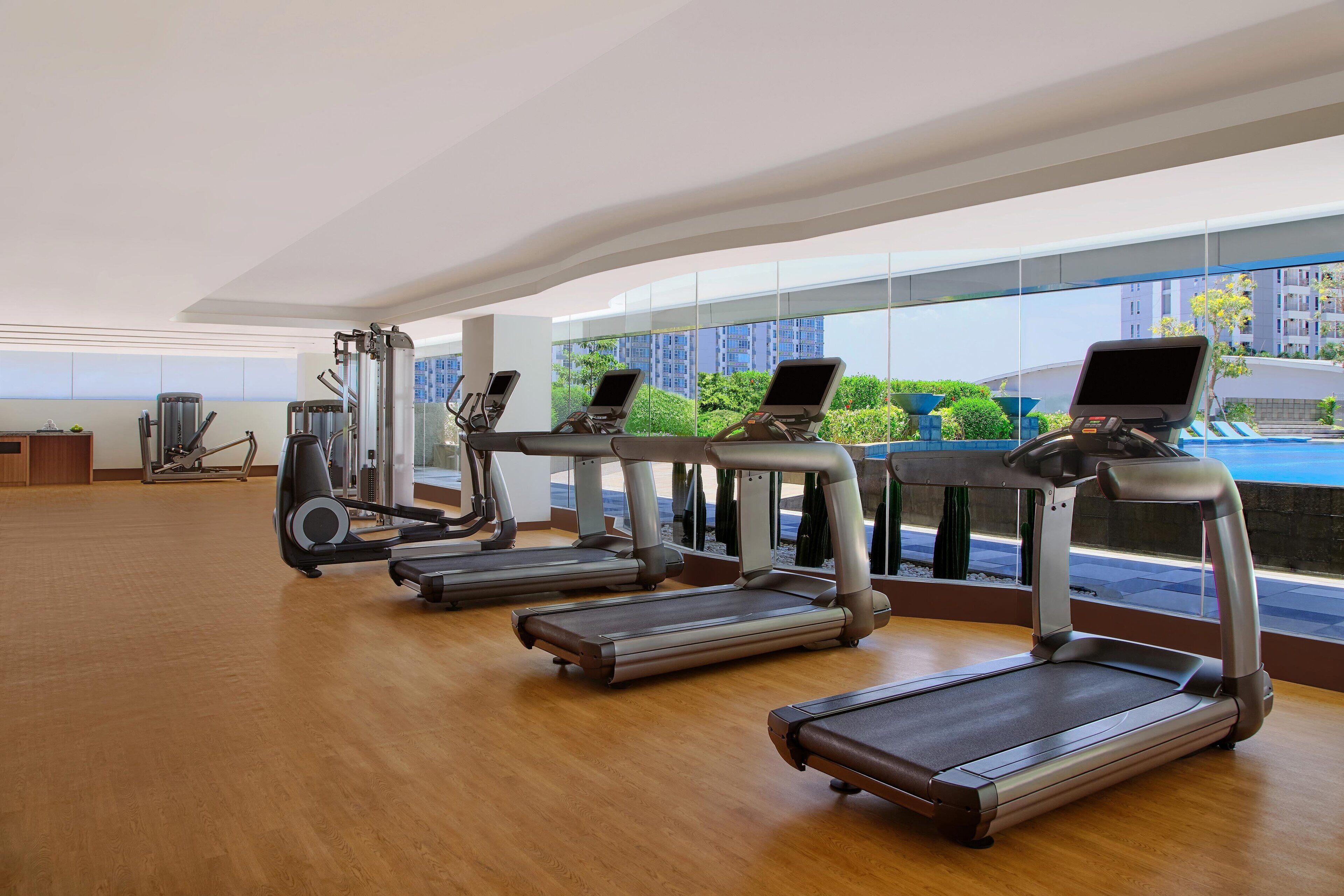 Un gimnasio con cintas de correr, elípticas y equipo de pesas.