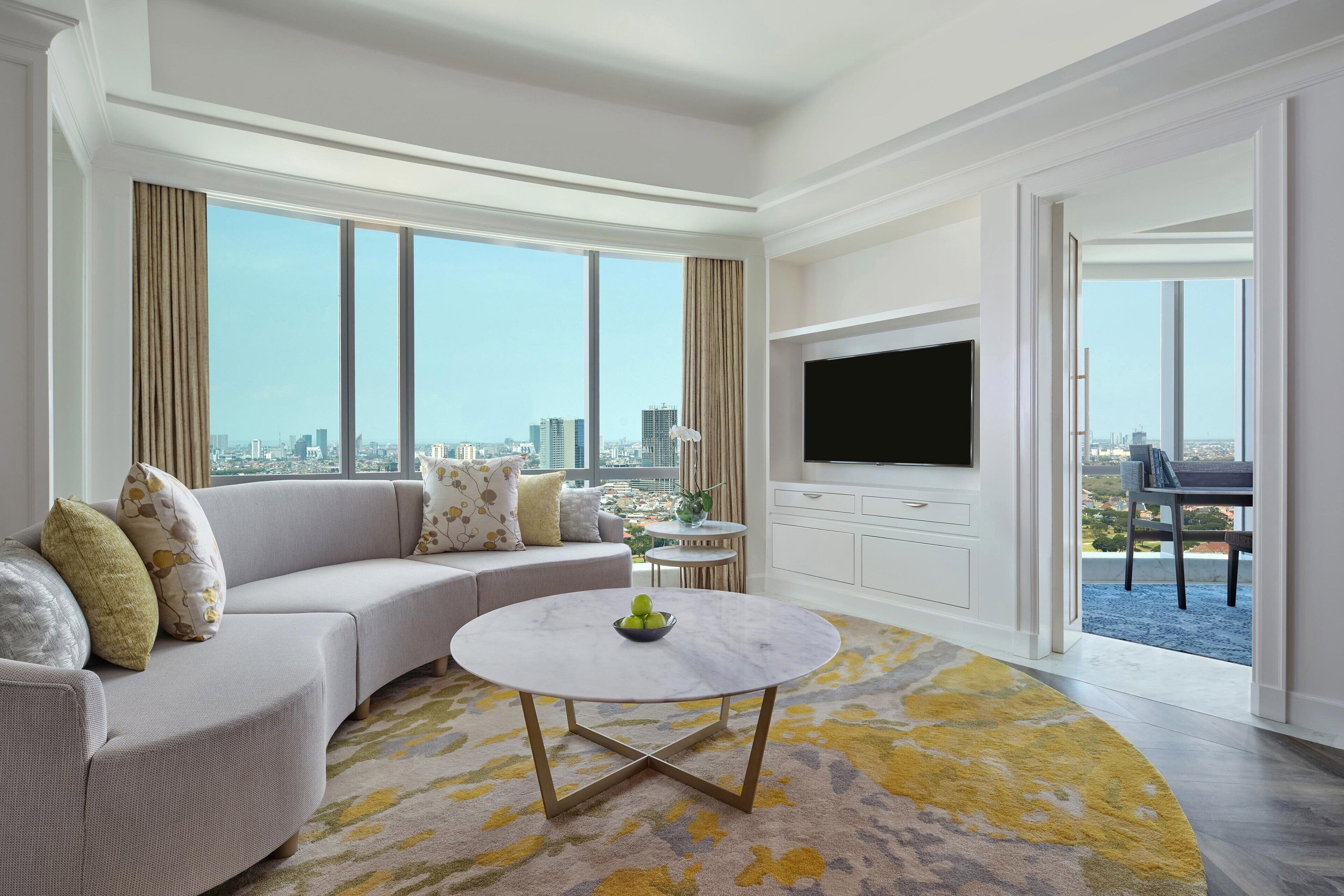 A modern living room with a sofa, a round coffee table, and a flat-screen TV.