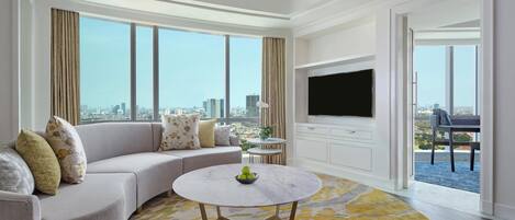 A modern living room with a sofa, a round coffee table, and a flat-screen TV.
