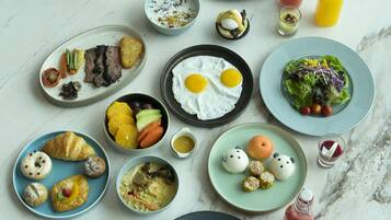 A variety of breakfast dishes on a marble table, including eggs, toast, and fruit.