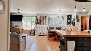 Une cuisine spacieuse avec un plancher en bois, un coin repas doté d’une table ronde et un coin salon confortable avec un canapé.