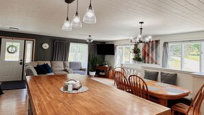 Une cuisine spacieuse avec un îlot central en bois, des luminaires suspendus et un coin repas comprenant des chaises et une table.