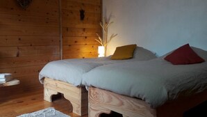 A wooden room with a bed, a heart-shaped decoration, and a small wooden cabinet.