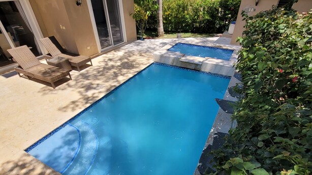 A rectangular swimming pool with a tiled edge, surrounded by a patio area with lounge chairs and a covered seating area. - Amazing Heated Jacuzzi, Private Pool, 2 Bed/Bath, AC in Everyroom!!!! (Sosúa)