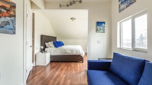 A bedroom with a bed, a nightstand, a blue sofa, and a window. - 5-bedroom home perfect for families/ groups. Located just minutes DT Vancouver (Vancouver)