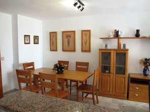 A dining area with a wooden table and chairs, a granite countertop, and a wooden cabinet with glass doors.