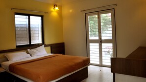 Une chambre à coucher avec un lit, une fenêtre avec des stores, une porte donnant sur une vue agréable et un luminaire fixé au mur.