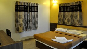Une chambre d’hôtel avec un lit, des rideaux, un bureau et une chaise.